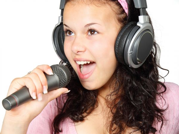 Photo of a girl with headphones singing in a microphone