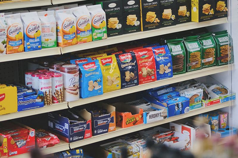 A supermarket shelf full of pre-packaged snack foods.