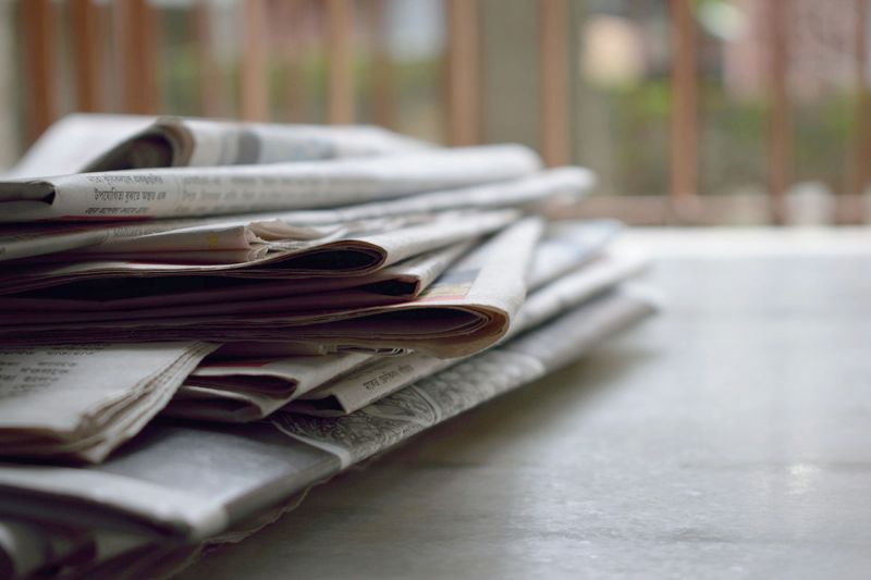 A stack of newspapers on a sunny table.
