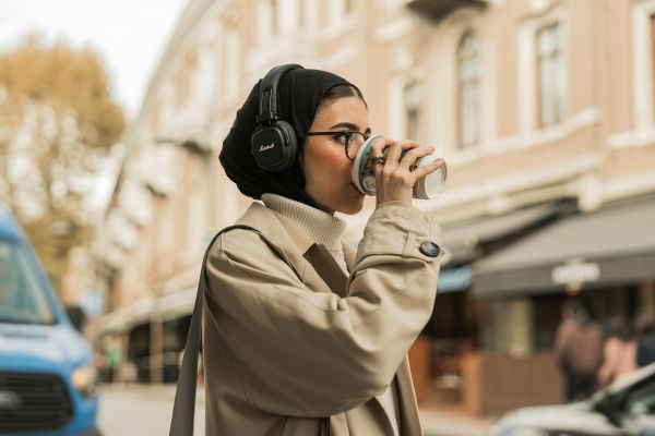 A woman drinking coffee while wearing headphones  